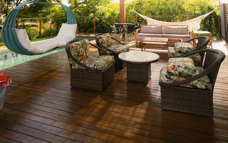 Outdoor patio with rattan seating, a hanging swing chair and a wooden pergola